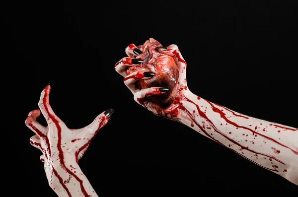 Blutiger Horror und Halloween-Thema: schrecklich blutige Hände mit schwarzen Nägeln, die ein blutiges menschliches Herz auf schwarzem Hintergrund im Studio halten — Stockfoto