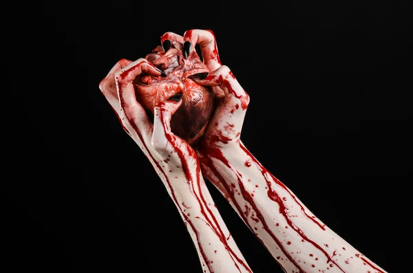 Bloody horror and Halloween theme: Terrible bloody hands with black nails holding a bloody human heart on a black background isolated background in studio — Stock Photo, Image