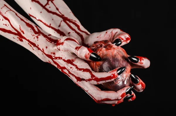 血まみれのホラーとハロウィーンのテーマ: 黒い背景に血まみれの人間の心を保持している黒の爪恐ろしい流血手分離スタジオの背景 — ストック写真