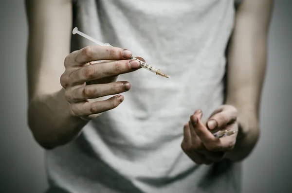 Kampen mot droger och narkotikamissbruk ämne: skinny smutsiga missbrukare håller en spruta med drogen och rött hjärta på en mörk bakgrund — Stockfoto