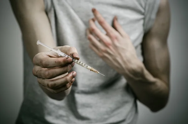 Η καταπολέμηση των ναρκωτικών και ναρκωτικών Τοξικομανίας θέμα: κοκαλιάρικο βρώμικο εξαρτημένος κρατώντας μια σύριγγα με ένα φάρμακο και το κόκκινο καρδιά σε σκούρο φόντο — Φωτογραφία Αρχείου