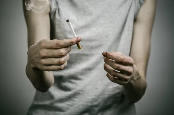 Τσιγάρα, τον εθισμό και θέμα δημόσιας υγείας: καπνιστής κατέχει το τσιγάρο στο χέρι και μια κόκκινη καρδιά σε σκούρο φόντο στο στούντιο — Φωτογραφία Αρχείου