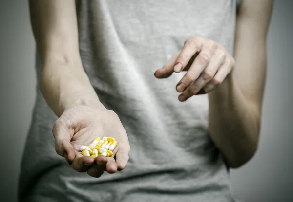 He fight against drugs and drug addiction topic: addict holding a narcotic pills on a dark background — Stock Photo, Image