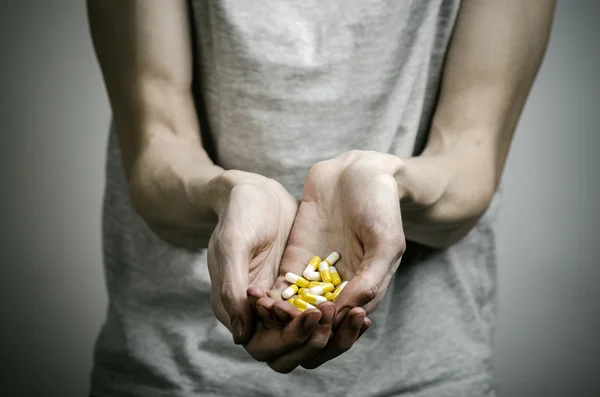 He fight against drugs and drug addiction topic: addict holding a narcotic pills on a dark background — Stock Photo, Image