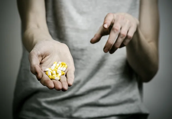 He fight against drugs and drug addiction topic: addict holding a narcotic pills on a dark background — Stock Photo, Image