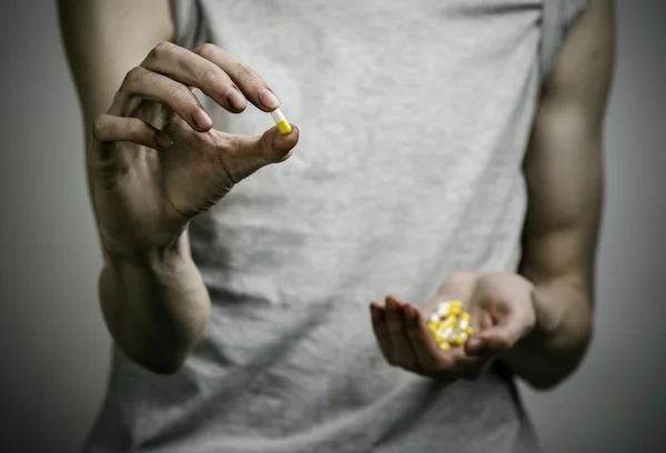 He fight against drugs and drug addiction topic: addict holding a narcotic pills on a dark background — Stock Photo, Image