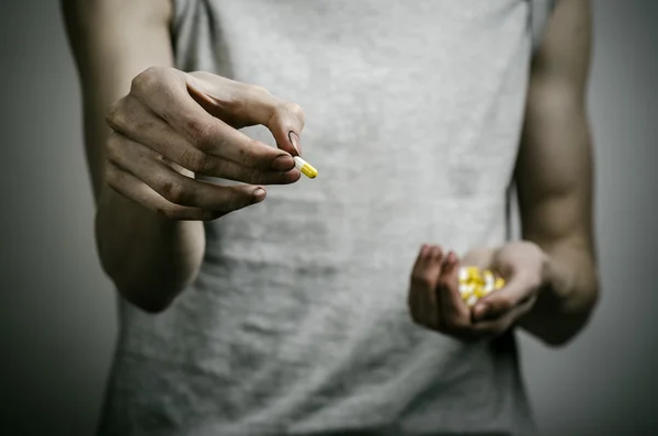 He fight against drugs and drug addiction topic: addict holding a narcotic pills on a dark background — Stock Photo, Image