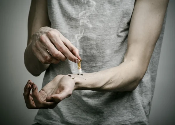 Zigaretten, Sucht und öffentliches Gesundheitswesen: Raucher legt die Hand auf die Zigarette vor dunklem Hintergrund — Stockfoto