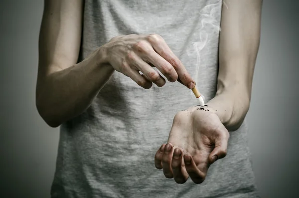 Papierosy, uzależnienie i zdrowia publicznego temat: palacz kładzie rękę na papierosa na ciemnym tle — Zdjęcie stockowe