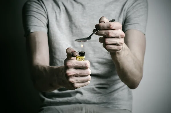 La lucha contra las drogas y la adicción a las drogas tema: adicto sosteniendo cuchara más ligero y calienta la droga líquida en una camiseta sobre un fondo oscuro — Foto de Stock