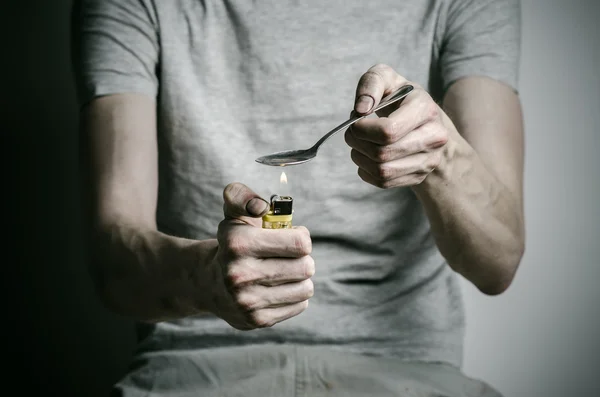 La lucha contra las drogas y la adicción a las drogas tema: adicto sosteniendo cuchara más ligero y calienta la droga líquida en una camiseta sobre un fondo oscuro — Foto de Stock