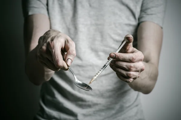 Boj proti drogám a drogové závislosti téma: narkoman držení lžíce světlejší a ohřívá kapalina drog v tričku na tmavém pozadí — Stock fotografie