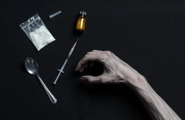 La lutte contre la drogue et la toxicomanie thème : dépendance à la main repose sur une table noire et autour de lui sont les drogues, un studio haut de gamme — Photo