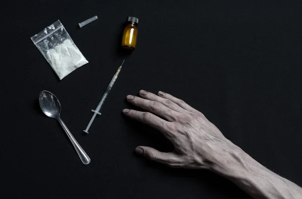 Boj proti drogám a drogové závislosti téma: ruka narkoman leží na tmavé stůl a kolem něj jsou léky, top studio — Stock fotografie