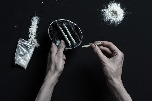 De strijd tegen drugs en drug verslaving onderwerp: hand verslaafde ligt op een donkere tafel en eromheen zijn drugs, een top studio — Stockfoto