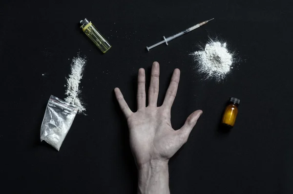 La lucha contra las drogas y la adicción a las drogas tema: adicto a las manos se encuentra en una mesa oscura y alrededor de ella son las drogas, un estudio de alto nivel — Foto de Stock