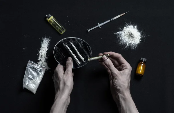 La lucha contra las drogas y la adicción a las drogas tema: adicto a las manos se encuentra en una mesa oscura y alrededor de ella son las drogas, un estudio de alto nivel — Foto de Stock