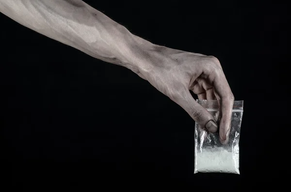 La lucha contra las drogas y la drogadicción tema: mano sucia sosteniendo una bolsa adicta a la cocaína en un fondo negro en el estudio — Foto de Stock