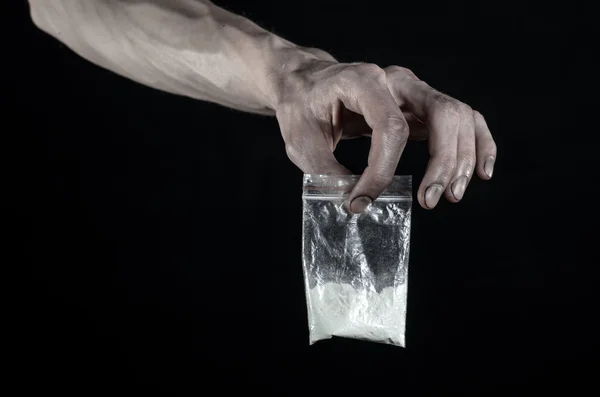 De strijd tegen drugs en drug verslaving onderwerp: vuile hand met een zak verslaafde cocaïne op een zwarte achtergrond in de studio — Stockfoto