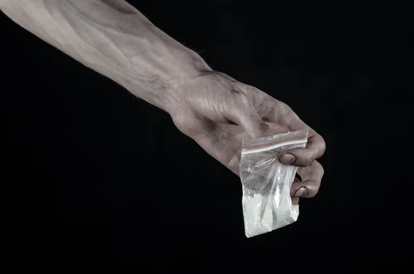 La lucha contra las drogas y la drogadicción tema: mano sucia sosteniendo una bolsa adicta a la cocaína en un fondo negro en el estudio — Foto de Stock