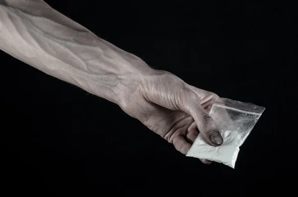 La lucha contra las drogas y la drogadicción tema: mano sucia sosteniendo una bolsa adicta a la cocaína en un fondo negro en el estudio —  Fotos de Stock