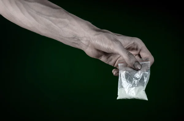 Boj proti drogám a drogové závislosti téma: špinavé ruce drží pytel narkomani kokainu na temně zeleném pozadí v ateliéru — Stock fotografie