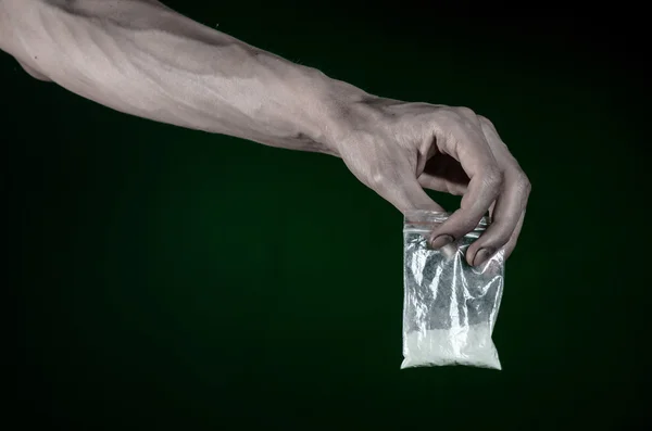 The fight against drugs and drug addiction topic: dirty hand holding a bag addict cocaine on a dark green background in the studio — Stock Photo, Image
