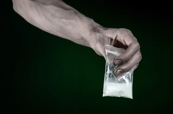 The fight against drugs and drug addiction topic: dirty hand holding a bag addict cocaine on a dark green background in the studio — Stock Photo, Image