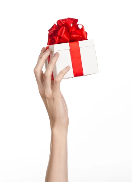 Das Thema der Feiern und Geschenke: Hand hält ein Geschenk in einer weißen Schachtel mit roter Schleife und Schleife verpackt, das schönste Geschenk isoliert auf weißem Hintergrund im Studio — Stockfoto