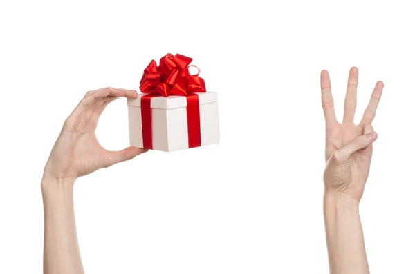 Das Thema der Feiern und Geschenke: Hand hält ein Geschenk in einer weißen Schachtel mit roter Schleife und Schleife verpackt, das schönste Geschenk isoliert auf weißem Hintergrund im Studio — Stockfoto