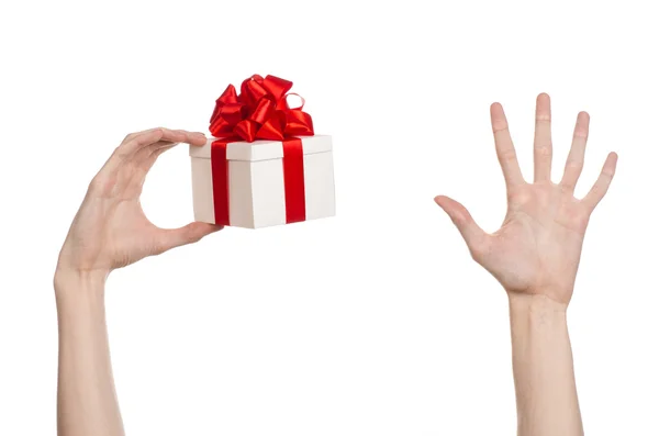 El tema de las celebraciones y regalos: la mano sosteniendo un regalo envuelto en caja blanca con cinta roja y lazo, el regalo más hermoso aislado sobre fondo blanco en el estudio — Foto de Stock