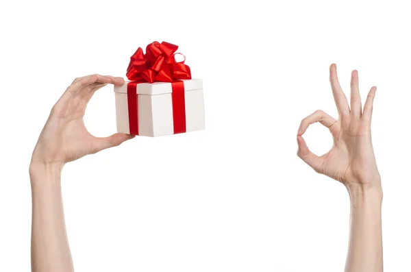 Il tema delle celebrazioni e dei regali: tenere in mano un regalo avvolto in scatola bianca con nastro rosso e fiocco, il regalo più bello isolato su sfondo bianco in studio — Foto Stock