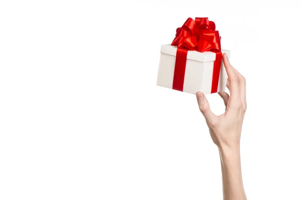 Das Thema der Feiern und Geschenke: Hand hält ein Geschenk in einer weißen Schachtel mit roter Schleife und Schleife verpackt, das schönste Geschenk isoliert auf weißem Hintergrund im Studio — Stockfoto