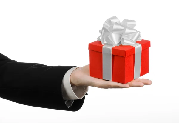 The theme of celebrations and gifts: a man in a black suit holding a exclusive gift wrapped in red box with white ribbon and bow, the most beautiful gift isolated on white background in studio — Stock Photo, Image