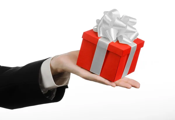 The theme of celebrations and gifts: a man in a black suit holding a exclusive gift wrapped in red box with white ribbon and bow, the most beautiful gift isolated on white background in studio — Stock Photo, Image