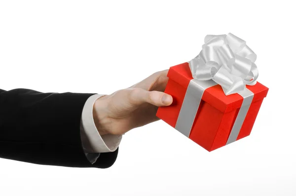 The theme of celebrations and gifts: a man in a black suit holding a exclusive gift wrapped in red box with white ribbon and bow, the most beautiful gift isolated on white background in studio — Stock Photo, Image