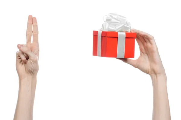 El tema de las celebraciones y regalos: la mano sosteniendo un regalo envuelto en caja roja con cinta blanca y lazo, el regalo más hermoso aislado sobre fondo blanco en el estudio — Foto de Stock