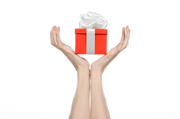 Il tema delle celebrazioni e dei regali: tenere in mano un regalo avvolto in scatola rossa con nastro bianco e fiocco, il regalo più bello isolato su sfondo bianco in studio — Foto Stock