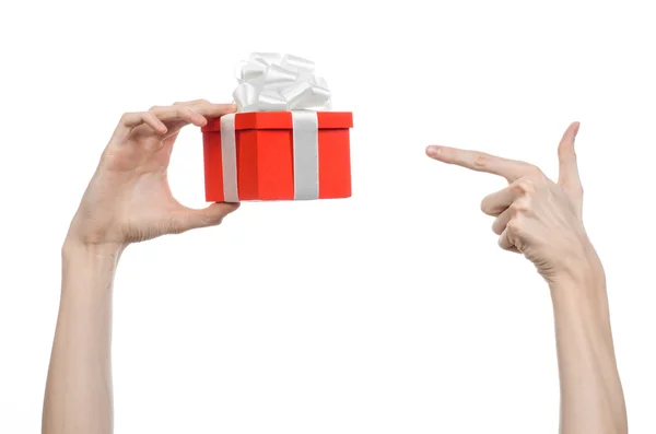 El tema de las celebraciones y regalos: la mano sosteniendo un regalo envuelto en caja roja con cinta blanca y lazo, el regalo más hermoso aislado sobre fondo blanco en el estudio — Foto de Stock