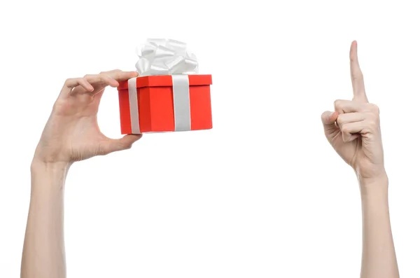 The theme of celebrations and gifts: hand holding a gift wrapped in red box with white ribbon and bow, the most beautiful gift isolated on white background in studio — Stock Photo, Image