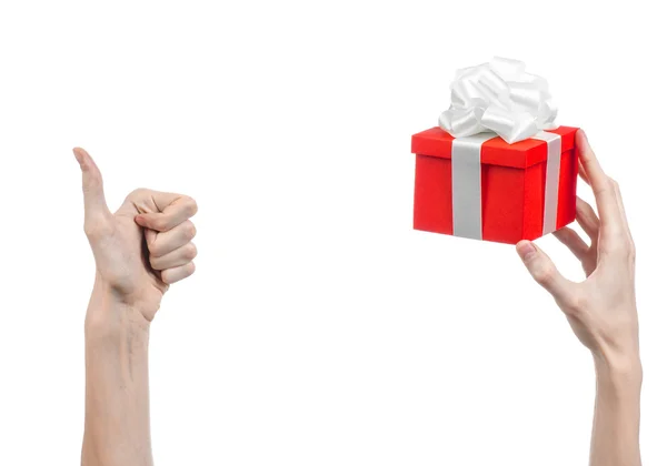 Temat för fester och gåvor: handen håller en gåva insvept i röd ruta med vita band och rosett, den vackraste gåva isolerad på vit bakgrund i studio — Stockfoto