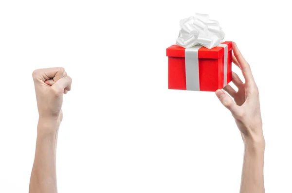 El tema de las celebraciones y regalos: la mano sosteniendo un regalo envuelto en caja roja con cinta blanca y lazo, el regalo más hermoso aislado sobre fondo blanco en el estudio — Foto de Stock