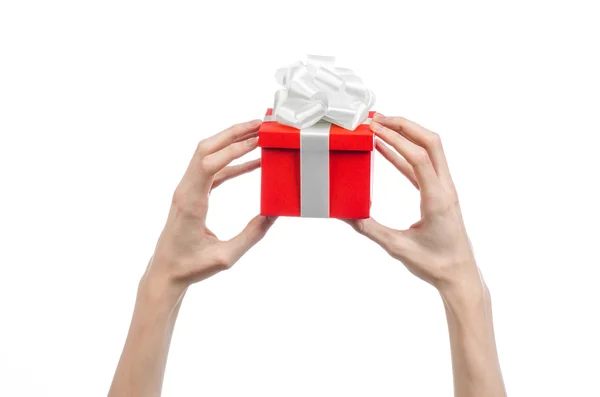 Το θέμα της γιορτές και δώρα: χέρι που κρατά ένα δώρο τυλιγμένο σε κόκκινο κουτί με λευκή κορδέλα και φιόγκο, το πιο όμορφο δώρο που απομονώνονται σε λευκό φόντο σε στούντιο — Φωτογραφία Αρχείου