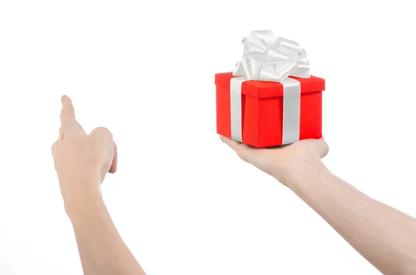 Het thema van vieringen en giften: hand met een geschenk verpakt in rode doos met wit lint en boog, het mooiste geschenk geïsoleerd op een witte achtergrond in studio — Stockfoto