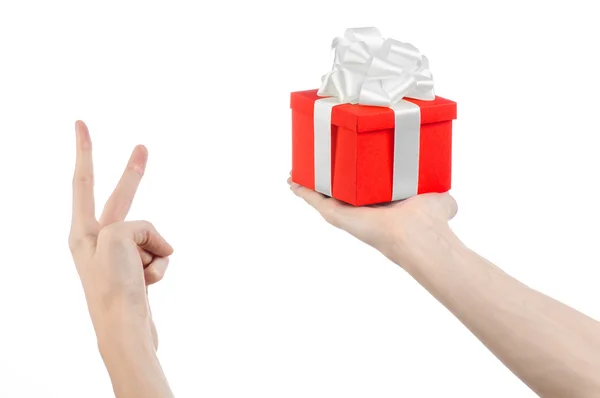 Temat för fester och gåvor: handen håller en gåva insvept i röd ruta med vita band och rosett, den vackraste gåva isolerad på vit bakgrund i studio — Stockfoto