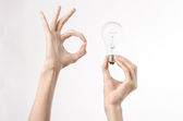 Az energiafogyasztás és az energia-megtakarítási téma: emberi kezében egy villanykörte stúdióban fehér alapon