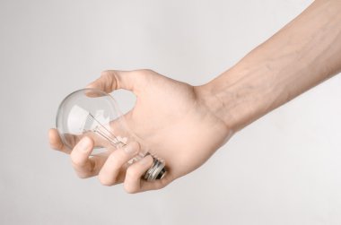 Enerji tüketimi ve enerji tasarrufu Konu: Studio beyaz zemin üzerinde bir ampul tutan eller