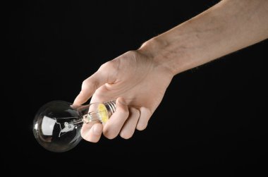Enerji tüketimi ve enerji tasarrufu Konu: Studio siyah arka plan üzerine bir ampul tutan eller