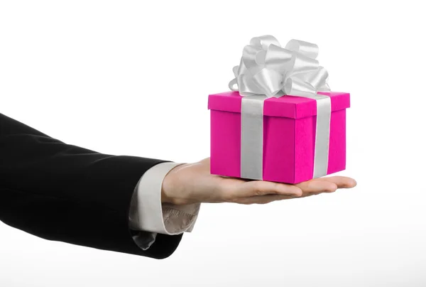 The theme of celebrations and gifts: hand holding a gift wrapped in pink box with white ribbon and bow, the most beautiful gift isolated on white background in studio — Stock Photo, Image