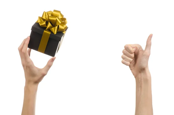 庆祝活动和礼品的主题: 手拿着礼物包裹金丝带与弓，最美的礼物孤立在工作室中的白色背景上的黑色方框 — 图库照片